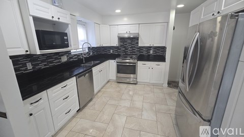 A kitchen with white cabinets and black countertops.