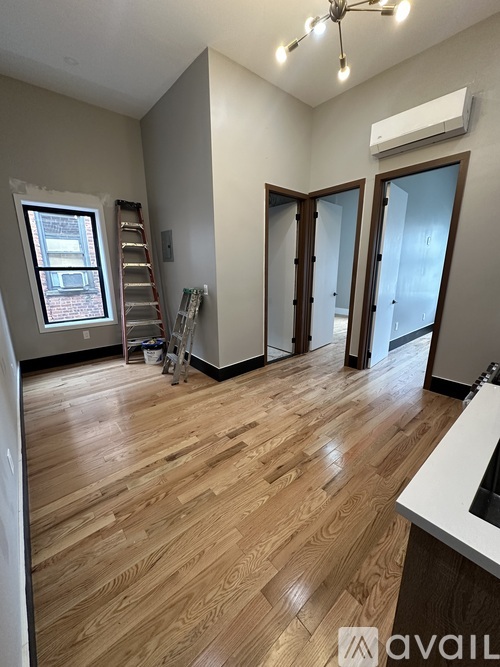 A room with wooden floors and a window with a ladder in front of it.