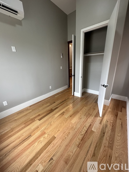 A room with wooden flooring and a doorway leading to another room.