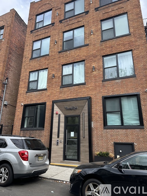 A black car is parked in front of a brick building.