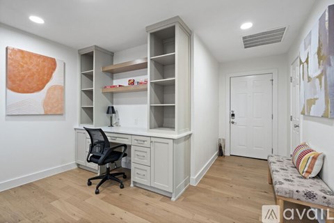 A room with a desk, chair, and built-in shelves.