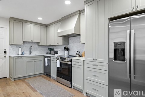 A kitchen with a refrigerator on the right and a sink in the middle.