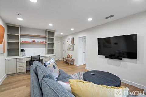 A living room with a grey couch and a black television.