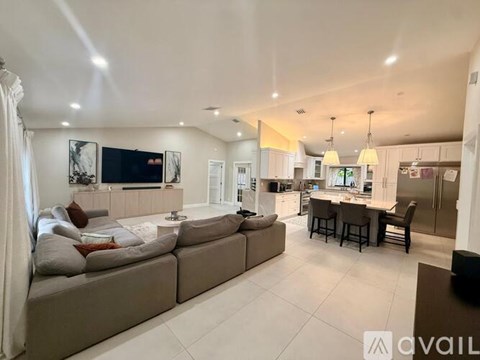 A spacious living room with a grey sofa and a television.