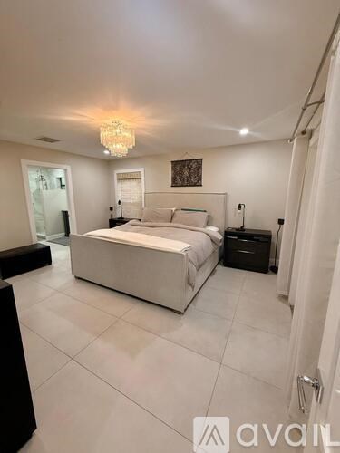 A bedroom with a large bed, a chandelier, and a painting on the wall.