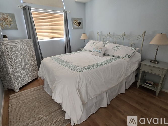 A bedroom with a white bed and a grey headboard.