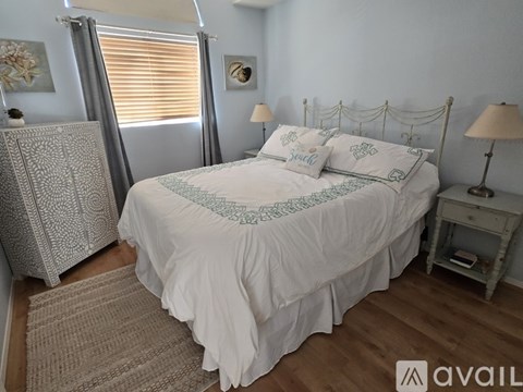 A bedroom with a white bed and a grey headboard.
