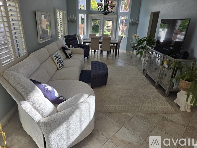 A living room with a white couch and a blue ottoman.