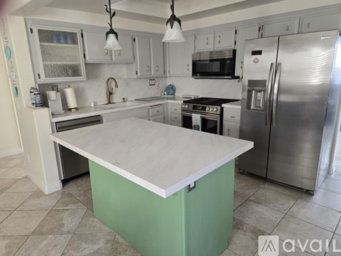 A kitchen with a green island in the middle of it.