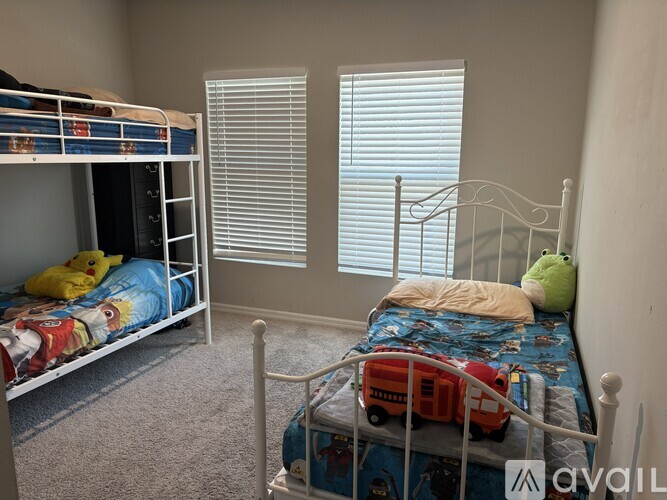 A bedroom with two bunk beds and a single bed with toys on it.