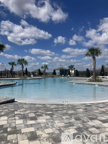 A large swimming pool surrounded by palm trees and a cloudy sky.