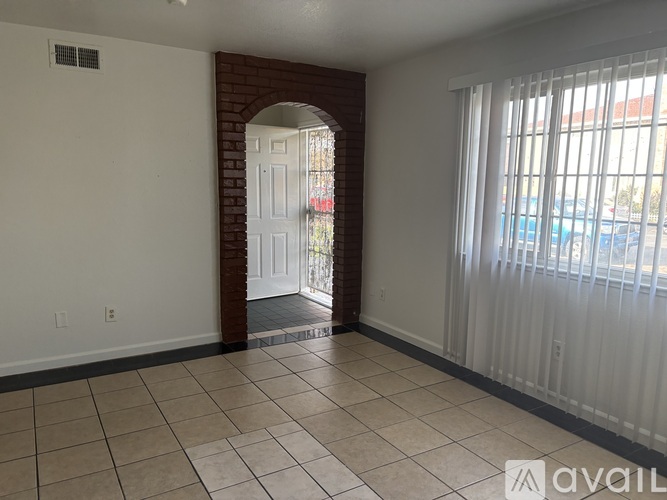 A room with a white door and a brick archway.