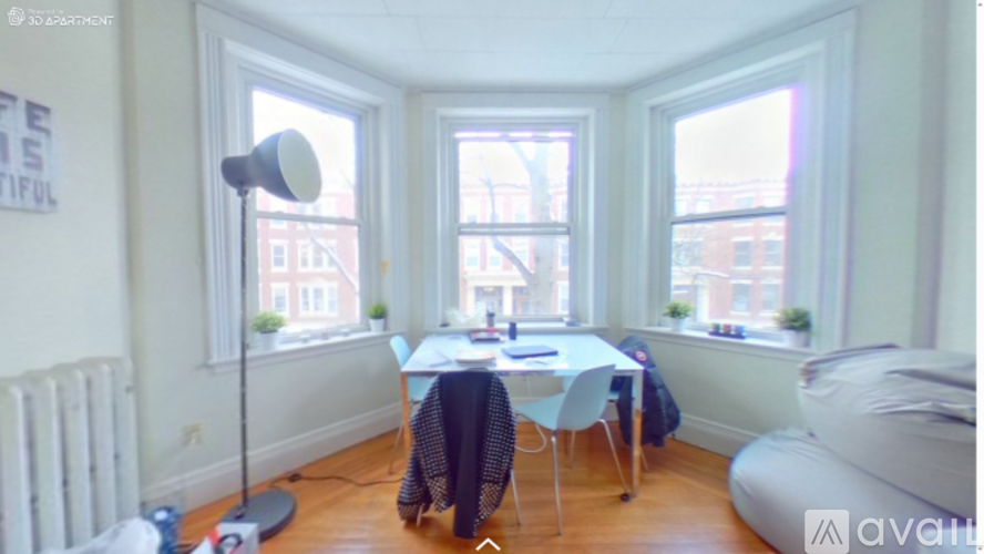 A room with a table and chairs in front of a window.