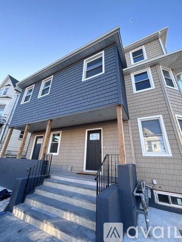 A modern two-story house with a black front door and a balcony.