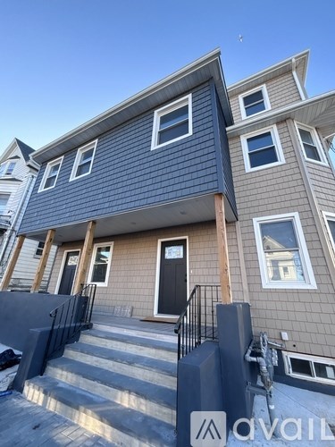 A modern two-story house with a black front door and a balcony.