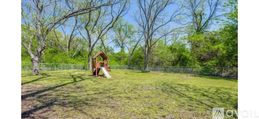 A playground with a slide is surrounded by trees.