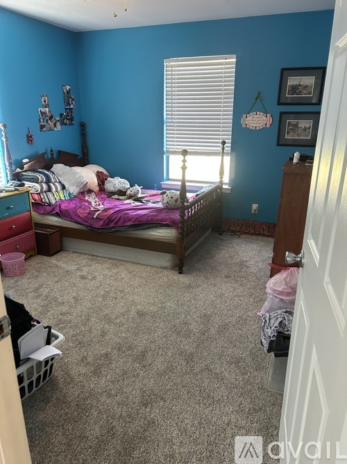 A bedroom with a bed, dresser, and window.