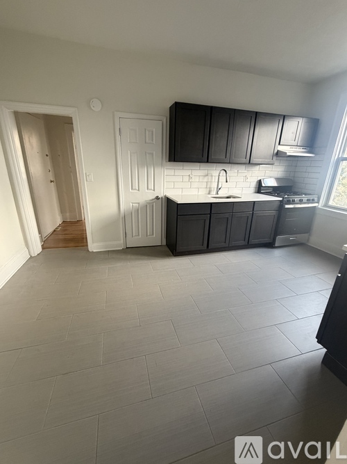 A kitchen with black cabinets and a white fridge.