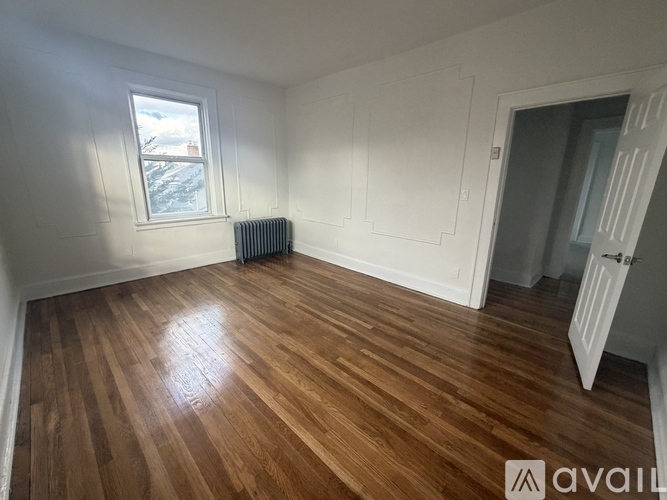 A room with wooden flooring and a window with a view of a snowy landscape outside.