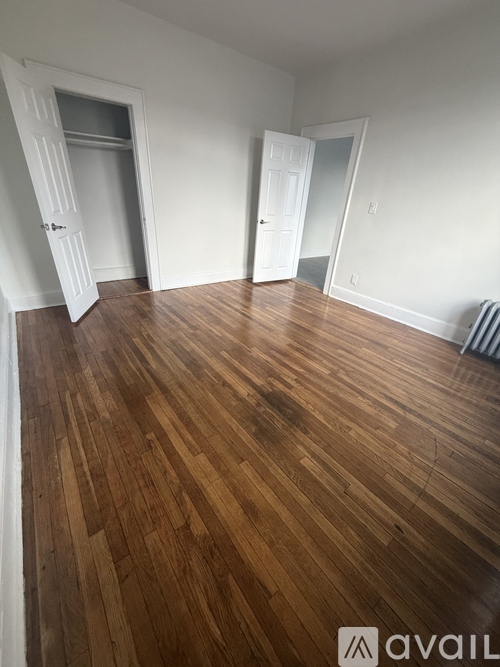 A room with wooden flooring and two white doors.