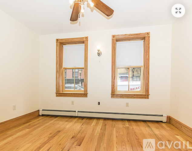 A room with wooden floors and two windows.