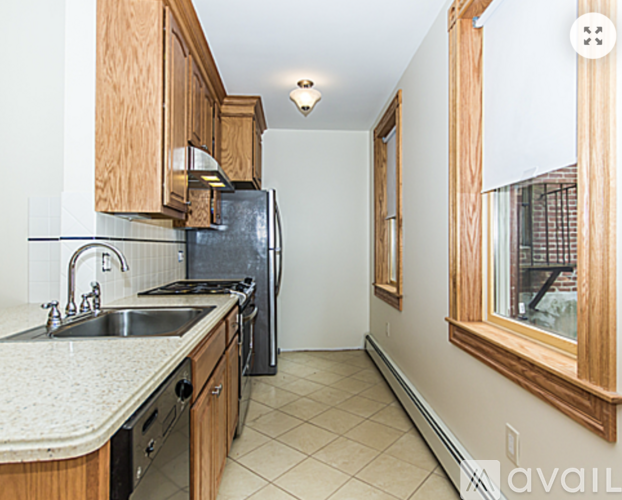 A kitchen with wooden cabinets and a black refrigerator.