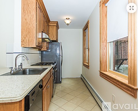 A kitchen with wooden cabinets and a black refrigerator.