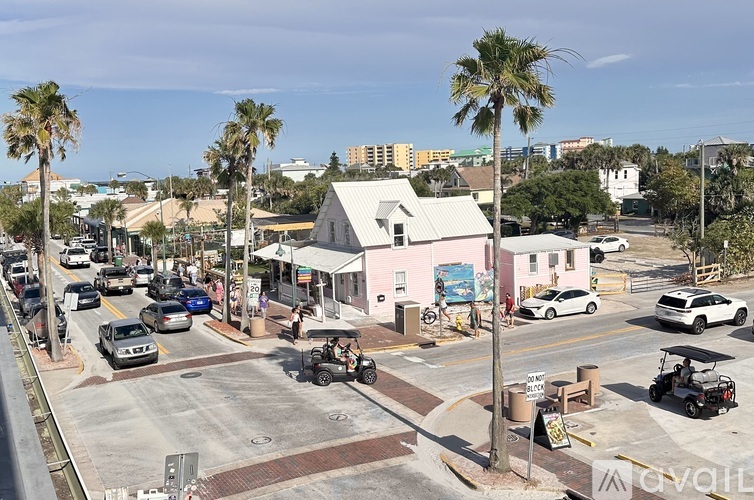 A street view of a town with cars and palm trees.