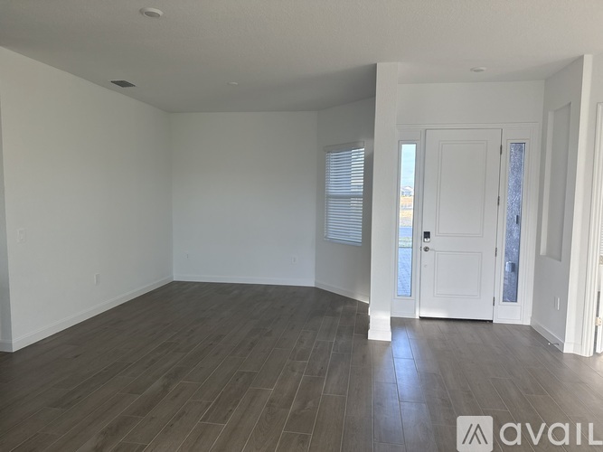 A spacious room with wooden flooring and white walls.