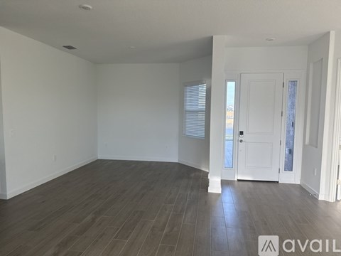 A spacious room with wooden flooring and white walls.