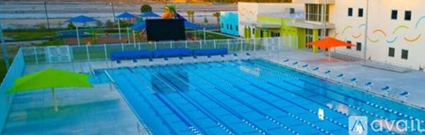 A large blue swimming pool with a white building in the background.