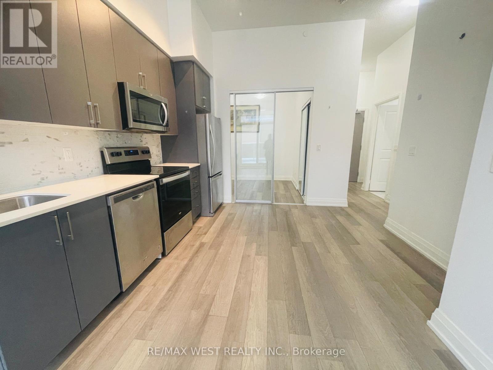 A kitchen with a refrigerator, microwave, oven, and sink.