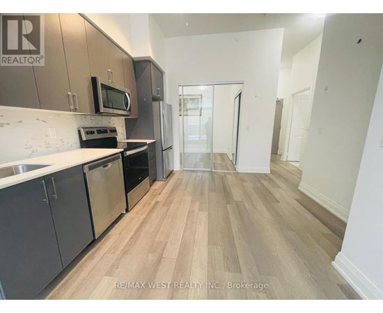 A kitchen with a refrigerator, microwave, oven, and sink.