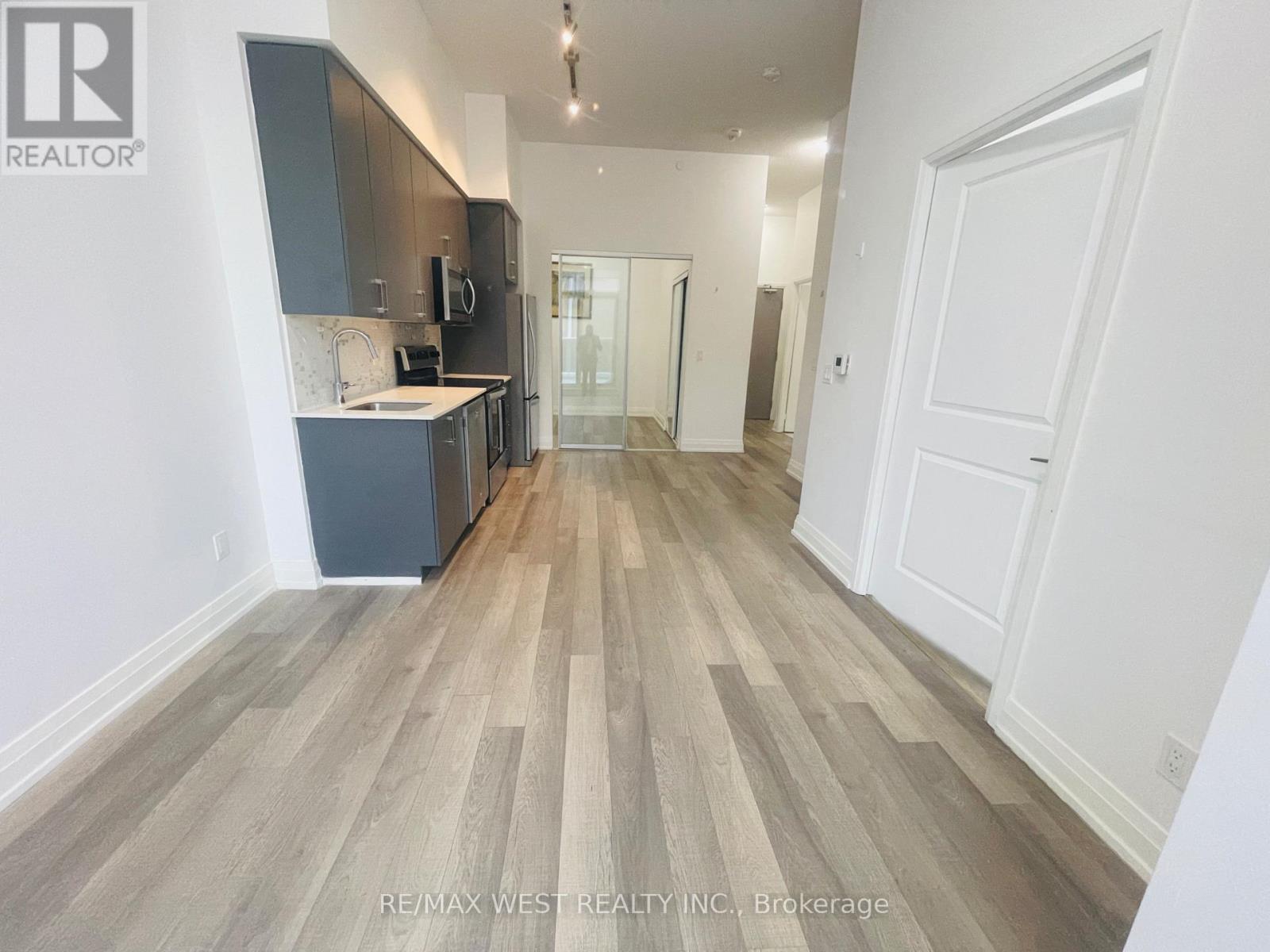 A spacious room with wooden flooring and white walls.