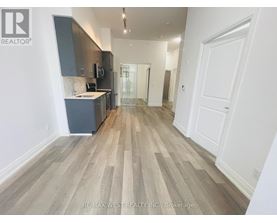 A spacious room with wooden flooring and white walls.