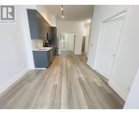 A spacious room with wooden flooring and white walls.