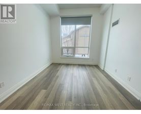 A room with wooden flooring and a window showing a building outside.