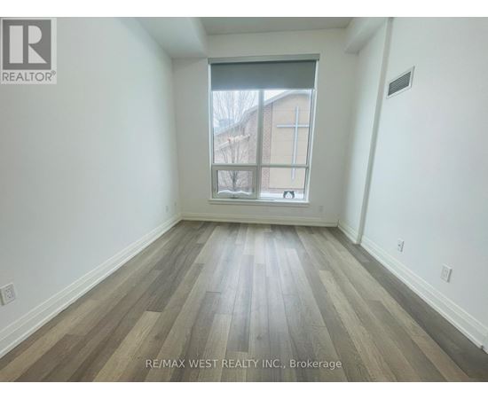 A room with wooden flooring and a window showing a building outside.