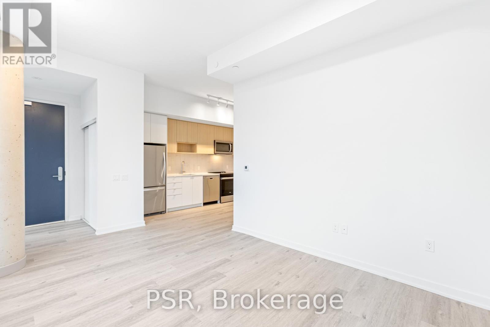 A spacious room with a kitchen area in the background.
