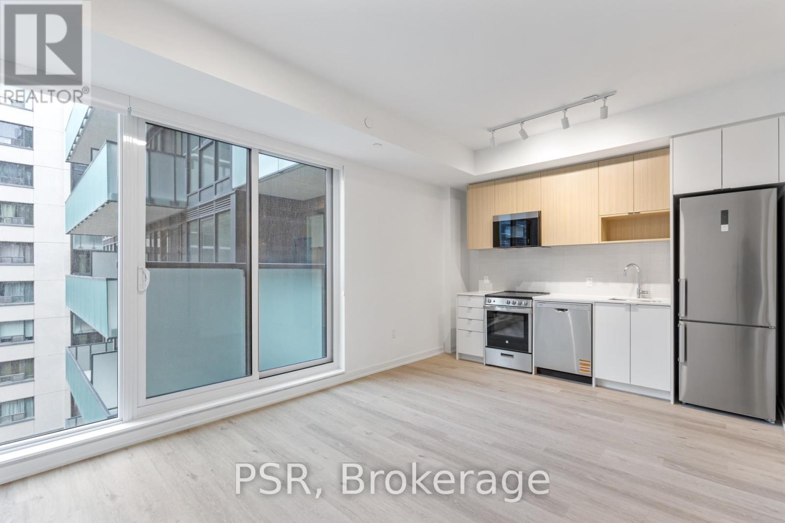 A kitchen with a refrigerator, oven, and microwave in a modern apartment.