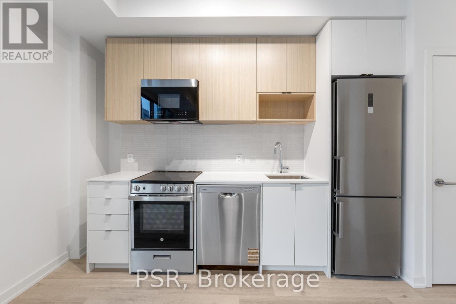 A kitchen with a refrigerator, oven, and sink.