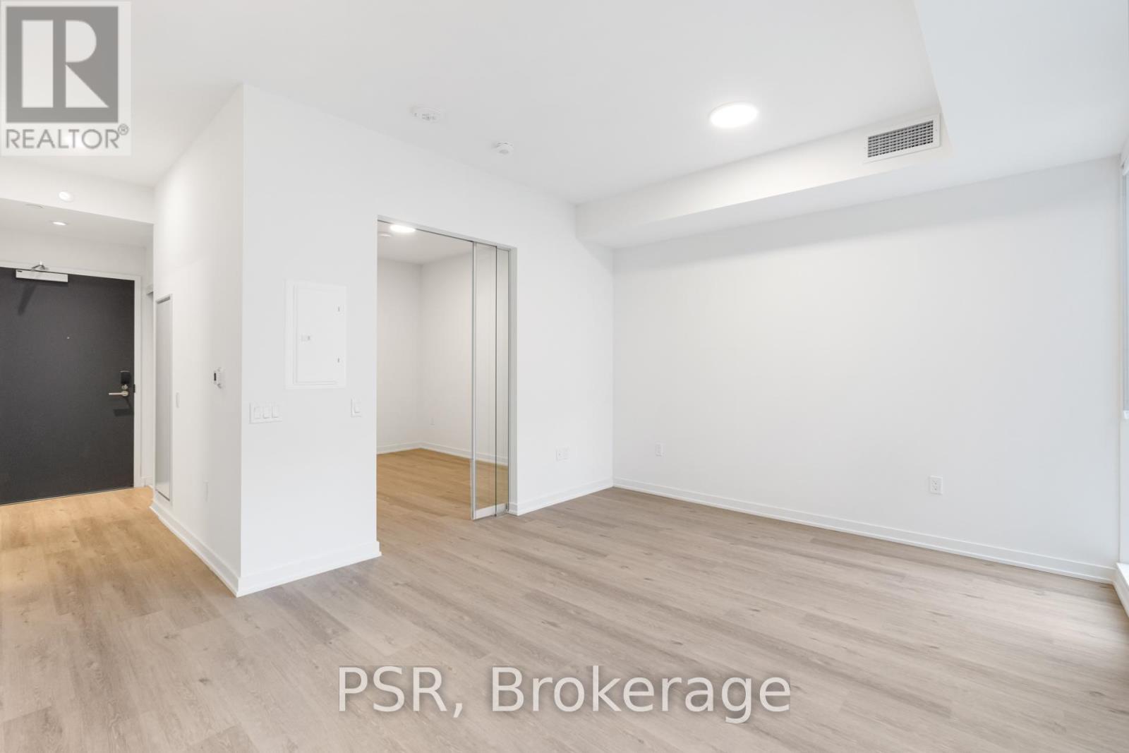 A spacious room with wooden flooring and white walls, labeled "PSR, Brokerage".