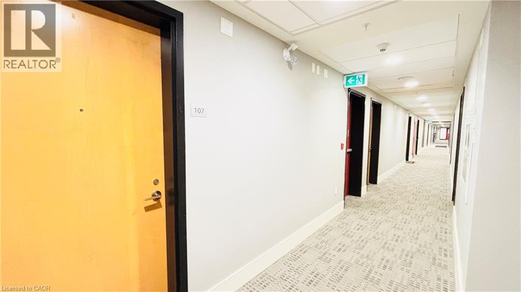 A hallway with a door on the left and a green exit sign above the door.