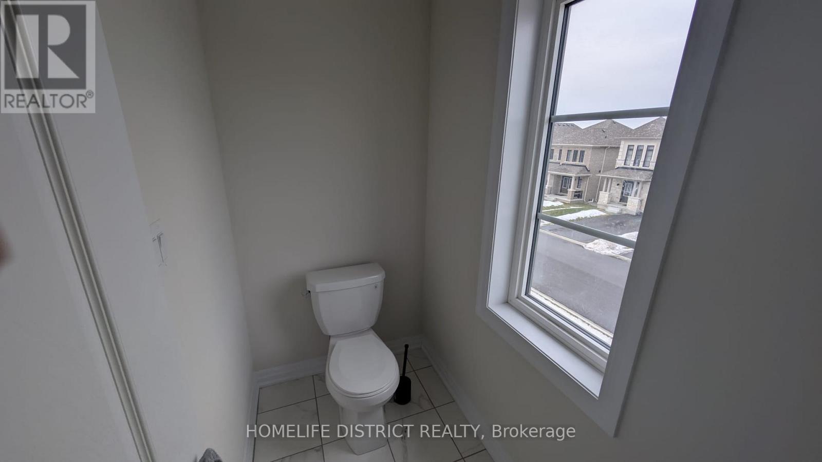 A bathroom with a toilet and a window overlooking a street.