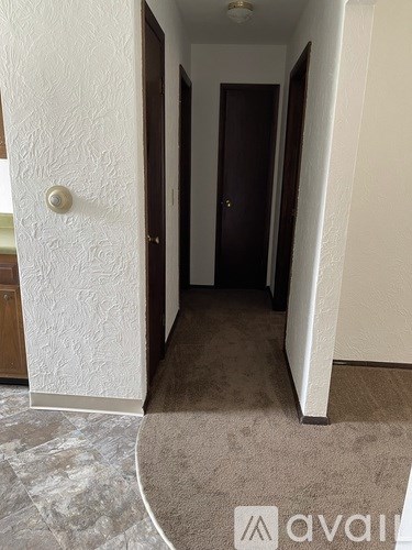 A hallway with a carpeted floor and a door on the right.