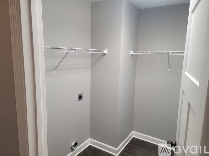 A small, empty room with a white door and a white wall.