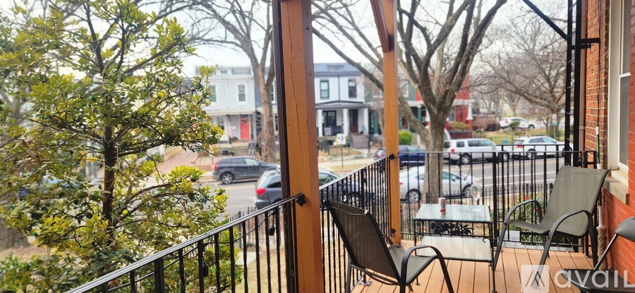 A balcony with a table and chairs overlooks a street.