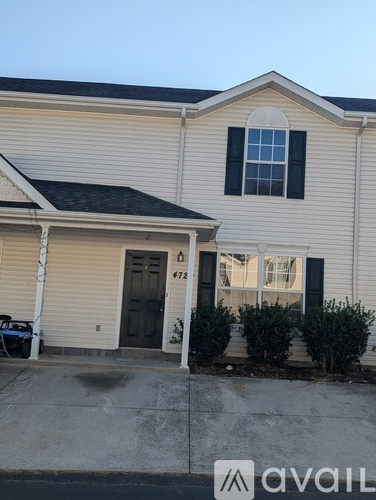 A beige house with a black door and windows.