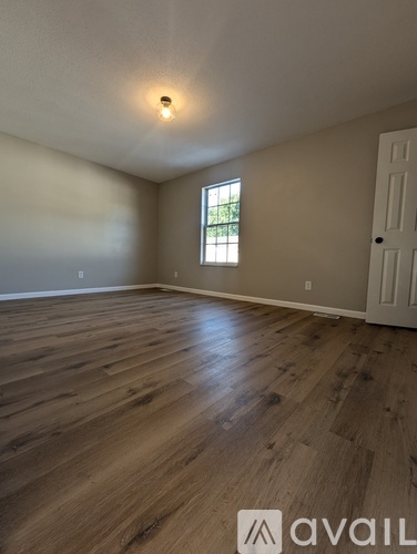 A room with wooden flooring and a window.