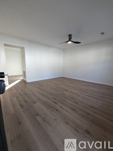 A room with wooden flooring and a ceiling fan.